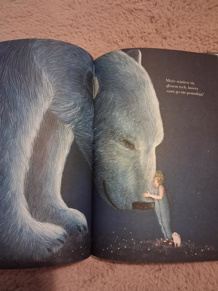 Wiara w siebie – dziecko w niebieskim stroju przytula ogromnego białego niedźwiedzia, obok stoi mały prosiaczek. Ilustracja z książki „Może” Kobi Yamady symbolizująca odwagę, empatię i wewnętrzną siłę.