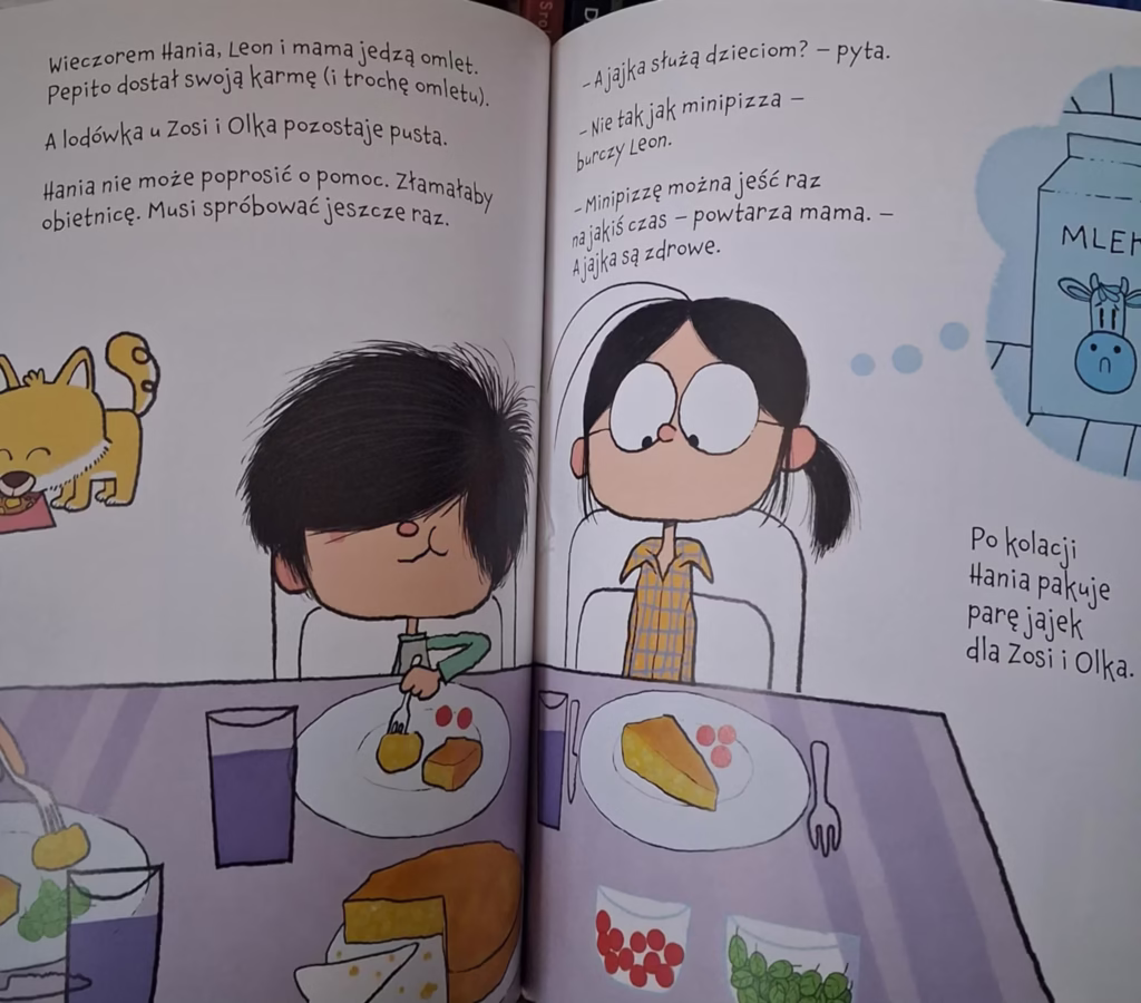 Hania siedzi z rodziną przy stole i je omlet, obok pustej lodówki Zosi i Olka – ilustracja z książki „Lodówka Zosi” Lois Brandt o empatii i dzieleniu się z innymi.